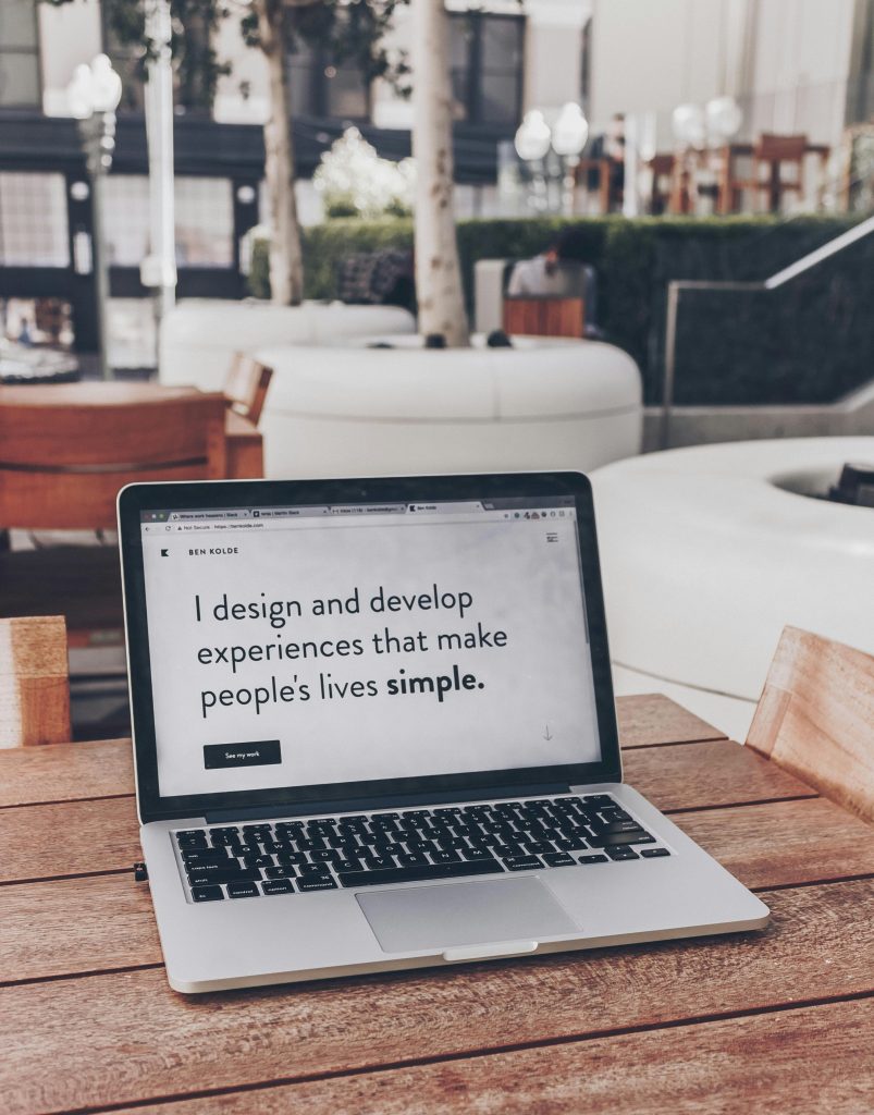 A laptop screen that says "I design and develop experiences that make people's live simple."